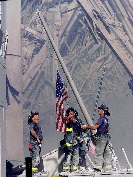 FDNY Firefighters raise an American flag where one of the World Trade Center towers once stood. Photo by Thomas E. Franklin/The Record